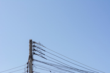 Electrical pole with messy wires connect on blue sky  background.