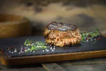 filet mignon steak lezhin on a stone and wooden stand, decorated with microgreens and large salt crystals, rustic style, close-up