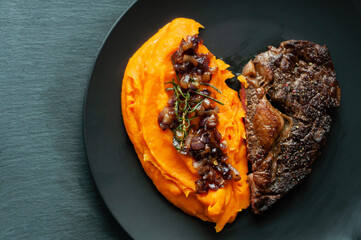 beef steak with carrot puree, caramelized red onion and rosemary, delicious and beautiful food, restaurant food at home, healthy food, proper nutrition, heart-shaped romantic dinner on a black plate