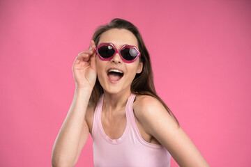 Stressed or having a headache businesswoman in suit holding her head with eyes shut isolated on pink background. Stressed employee woman in stripe suit