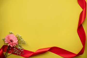 Obraz premium flower on a yellow background with a red ribbon. place for text