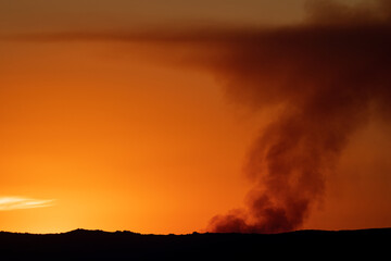 Obraz na płótnie Canvas Fire smoke over the orange horizon at sunset