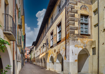 Fototapeta na wymiar Saluzzo, Italy - May 06, 2019: Via Alessandro Volta (via de porti scur) with Palace of the Bishops in the foreground and other ancient buildings in the historic center