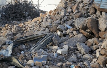 Stapel abgerissener Betonsteine und Bündel Stahldraht auf Baustelle bei Sonne im Winter