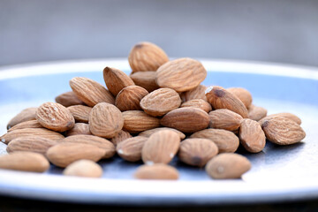 closeup the bunch brown almond nuts over out of focus grey brown background.