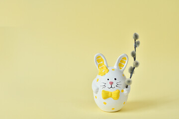 Happy Easter holiday concept, Cute bunny with pussy willow branches with catkins on yellow background. Greeting card.