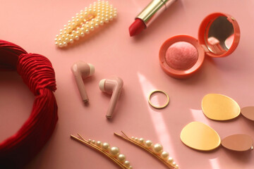 Pink bluetooth earphones, red hairband, pearl hair clips, gold earrings and ring, pink blush and...