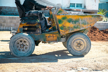 Obraz premium Profile view of Machinery (Dumper) working transporting concrete for the construction site with worker driving