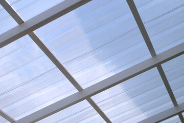 Under the structured white roof with sunlight and shadow