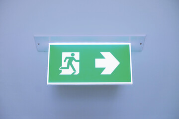 Front face raised view of green emergency fire exit sign hanging on the ceiling