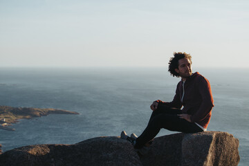 Man sitting on a rock looking at the sea