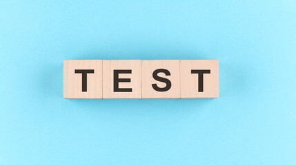 Wooden cube block with text TEST on the blue background