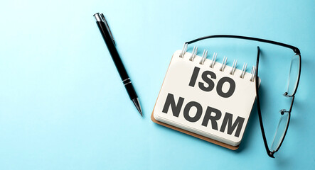 ISO NORM text written on a notepad on the blue background - obrazy, fototapety, plakaty
