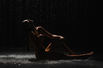 Girl with a beautiful figure on a black cyclorama under the shower - 488032616