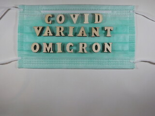 The word covid variant omicron in wooden letters on the face mask. High quality photo
