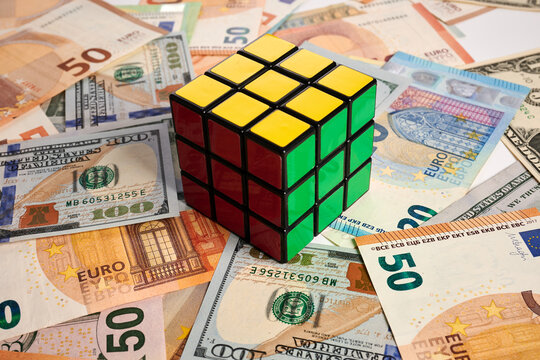Krasnoyarsk, Russia - February 04, 2022: Rubik cube - photo on cash bank notes. Colored Rubik cube is laying on cash bank notes. Dollar and Euro banknotes is a background for intellectual rebus.