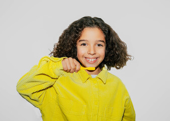 Smiling afro girl showing how she brushes her teeth. White background. Copy space. 