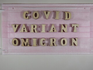 The word covid variant omicron in wooden letters on the face mask. High quality photo