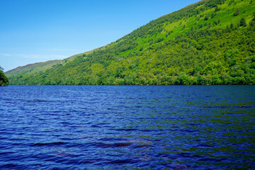 View of a deep blue lake and green hill side forest