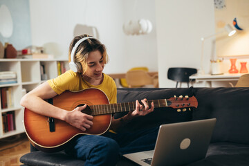 teenager playing guitar at home.