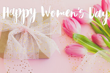 Happy womens day text on pink tulips and gift box  on pink background. Stylish greeting card....