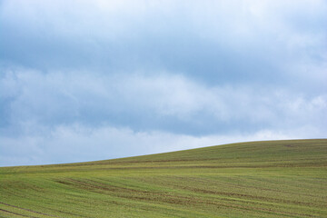 a deep blue sky over a green field on a hill