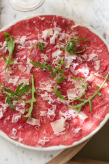 Traditional Beef Carpaccio Garnished with Parmesan Cheese and Fresh Arugula Leaves