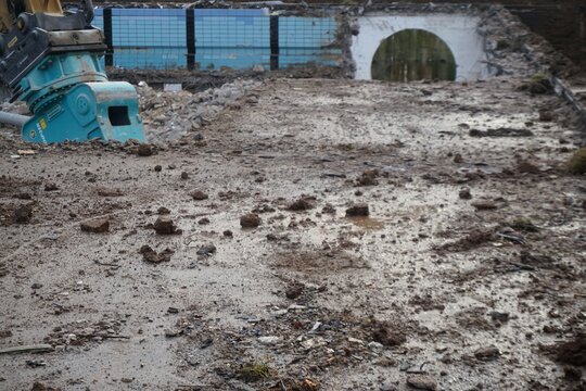 Schwimmbecken-Abriss mit blauer Baggerzange im Winter