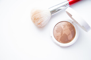 A white pillbox with powder and bronzer lies on a white background, next to it lies a blush brush with a place for text. High quality photo