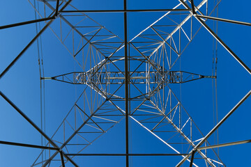 High voltage tower seen from underneath with blue sky