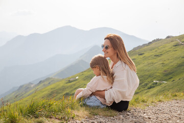 Mother with daughter sitting in mountains. Active family lifestyle.