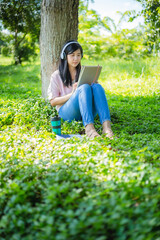 Asian woman reading a book and smiling in the park,Satisfied asian woman reading a book in a park