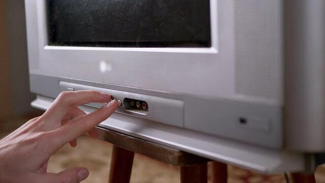 A Male Hand Presses the Buttons with Finger on Old Vintage TV with Interference. Switching channels. Problem with signal transmission. Static flickering noise interference, distortion, pixels, glitch.