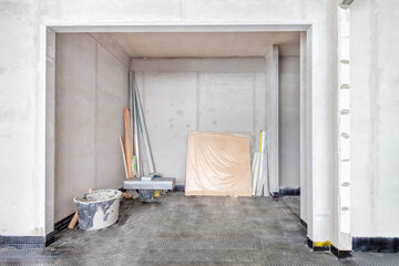 Warehouse buildings construction interior site with concrete walls and building materials in light room under repairing work.