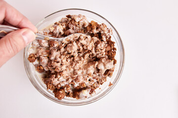 Mix granola with yogurt in a transparent bowl on a white background. Healthy food.
