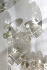 Various transparent beads on white background, illuminated by sunlight and reflectiing light. Flat lay.