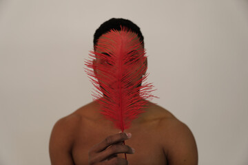 Portrait of American Indian warrior. Man with red feather. Fine-art photo.