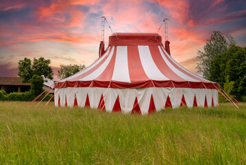 Colourful circus tent on green meadow against a colorful sunset sky - obrazy, fototapety, plakaty