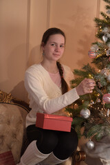 girl with christmas tree hangs toys