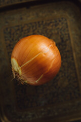 single yellow onion on Indian brass tray