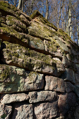 Ancient fragments of rock wall in the forest protecting road from landslide. Stone barrier.