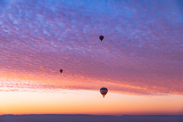 Hot air balloons flying over the Valley of the Kings during an amazing sunrise in Luxor, Egypt.
