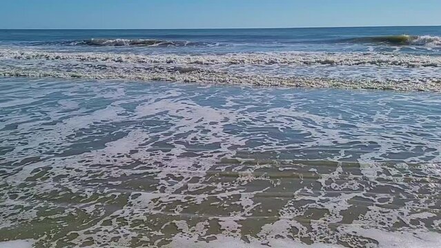 Ocean beach view blue sky's water waves crashing on the sands close to the shore