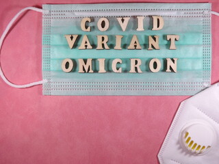The word covid variant omicron in wooden letters on the face mask. High quality photo