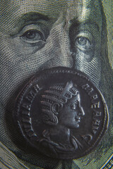 old rome coin stands on a hundred dollar bill closeup