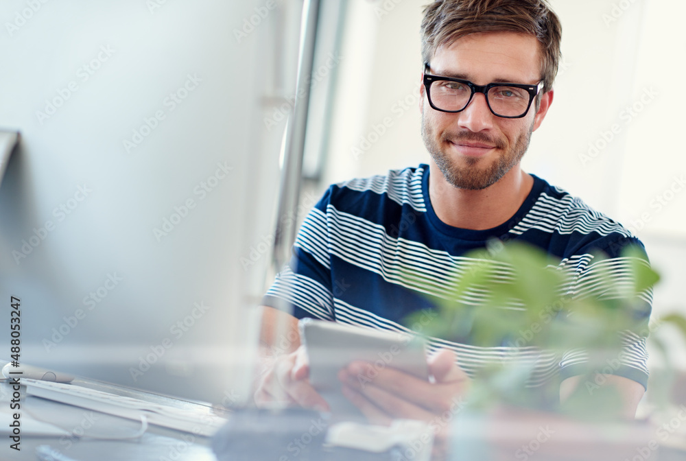 Poster designing tomorrows tech today. portrait of a casually-dressed young man using a digital tablet at h