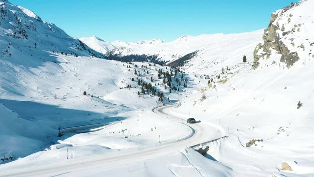 2022 - Excellent aerial view of a car driving on a snowy highway from Davos to St. Moritz, Switzerland.