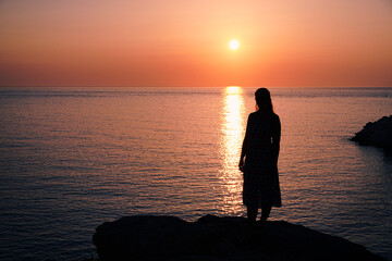 Fototapeta premium Silhouette of a woman on a sunset in Paros Island, Greece.