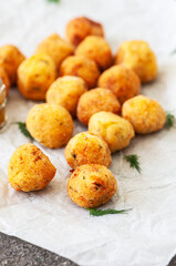 Deep fried potato cheese balls on a baking paper. Close up.