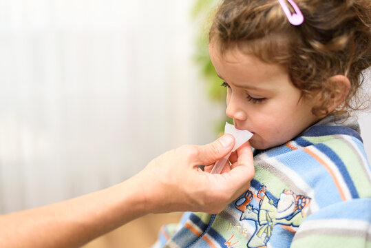 A three-year-old girl spits into a saliva test tube for covid19 antigens.
